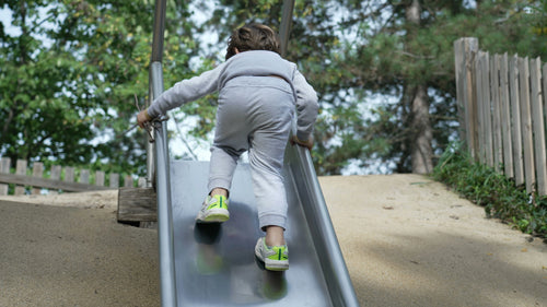 Child climbing up a playground slide instead of sliding down, unsupervised free play