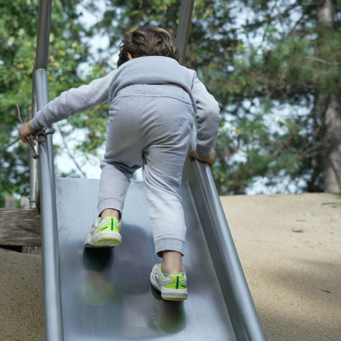 Child climbing up a playground slide instead of sliding down, unsupervised free play