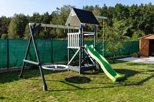 Wooden backyard swing set installed with safety surfacing and clearance around the frame