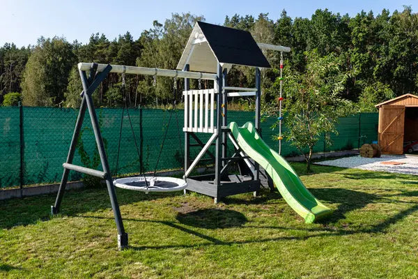 Wooden backyard swing set installed with safety surfacing and clearance around the frame