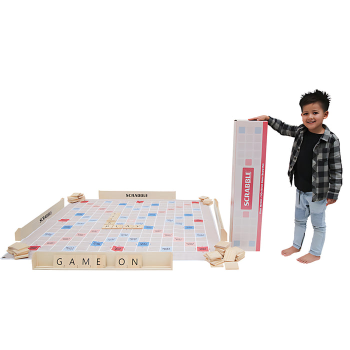 image of a boy holding the giant scrabble box standing next to the giant scrabble mat game set up