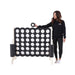 image of a lady standing next to the Giant 120cm connect 4 in Black and White