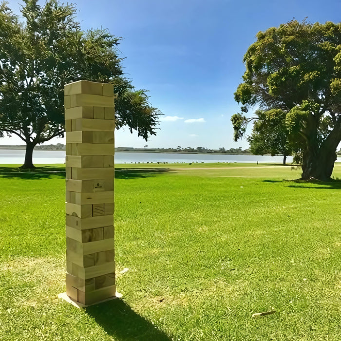 image of the 127cm giant jenga on grass with a lake in the background with trees