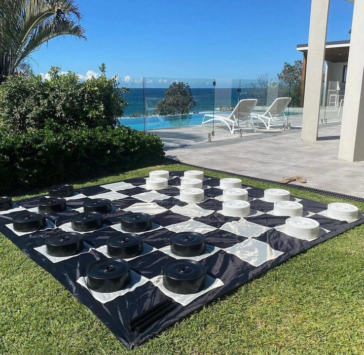 3 meter giant outdoor checkers outside set up on grass ready to play with a pool in the background