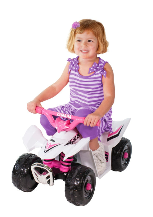 Little girl riding on a White and Pink Yamaha Mini Quad Bike TRX ATV with white background