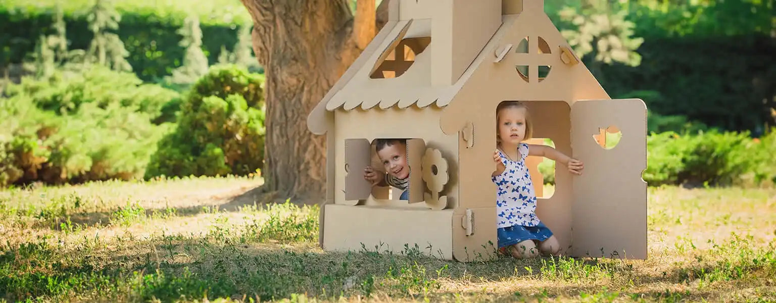 Cardboard playhouse with decorative cutout windows and a peaked roof.