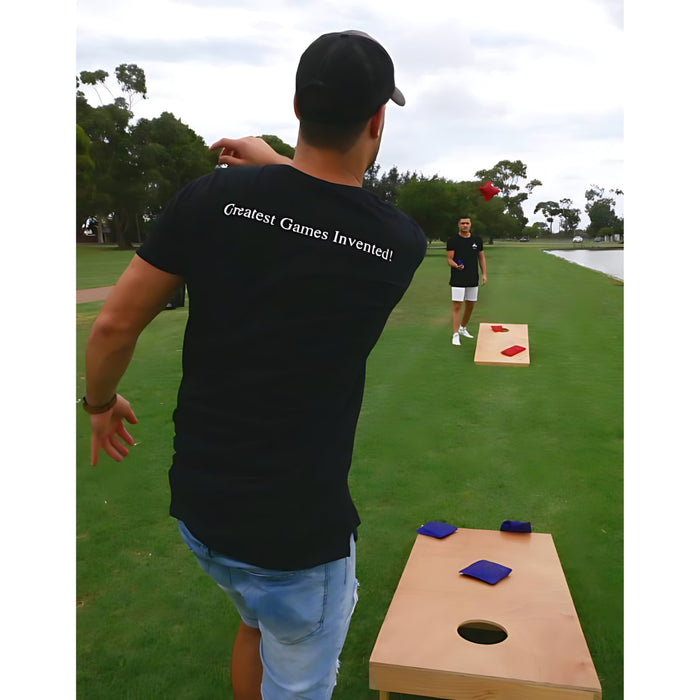 two men playing cornhole on grass you can see the cornholes and the bean bags