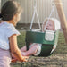 Two children playing with a green baby swing outdoors.