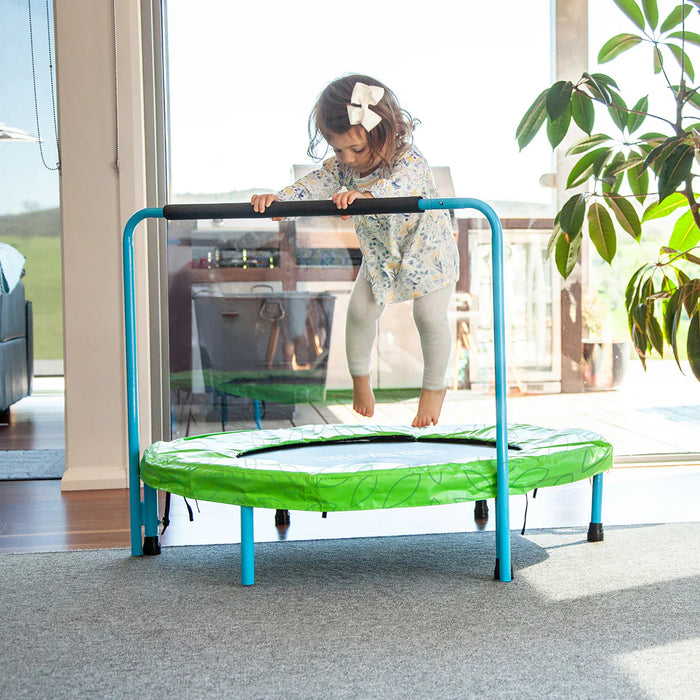 Child on a green trampoline indoors with a modern home background