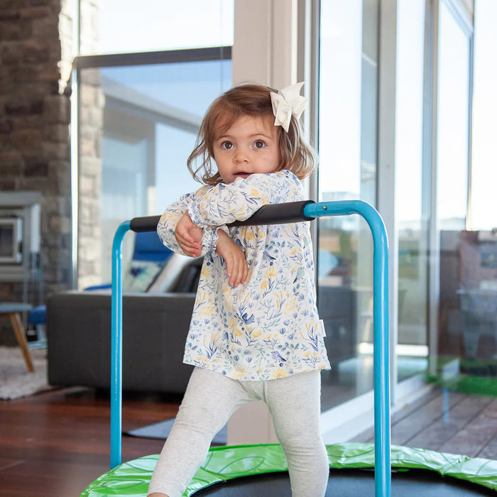 Child standing on a small trampoline indoors with a modern living room in the background