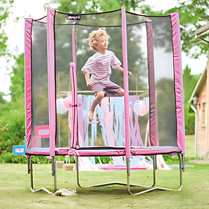 a boy jumping on a pink trampoline outside on grass