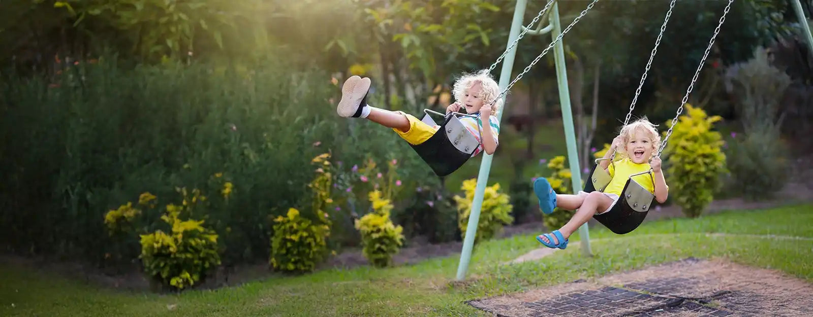 Two young children on swings in a park.
