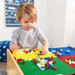 Close up image of  little boy playing legos on the 2 in 1 Lego Board and Table with room bakground