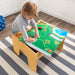 Slightly top view image of little boy playing with rails on the 2 in 1 Lego Board and Table with room bakground