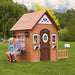 Full image of Aspen Cubby Playhouse with 2 children sitting on the side with outdoor background