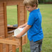 Close up image of a little boy opening the mailbox of Aspen Cubby Playhouse