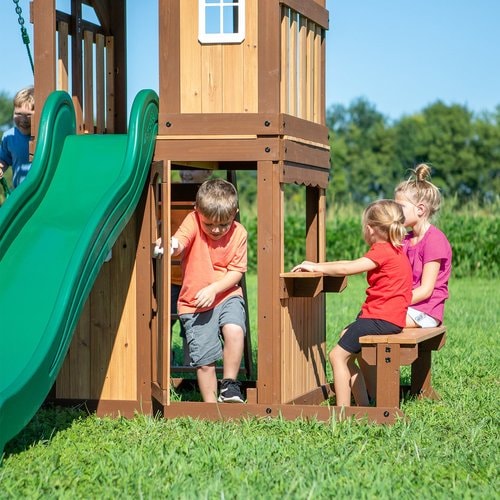 Close up image of a little boy going out from the entrance of the snack bar and two little girls sitting outside the snack bar of Lakewood Swing And Play Set