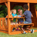 Close up image of children sitting and talking in the snack stand of Skyfort II Swing And Play Set