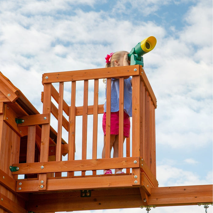 Close up image of a little girl on the lookout balcony of Skyfort II Swing And Play Set with the telescope