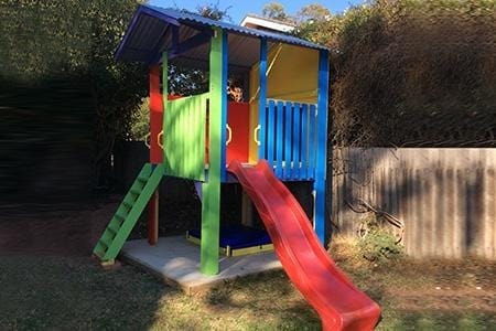 Medium Fort Cubby House - colourful design. painted in green, blue, orange and yellow with red slide