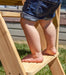 Close up image of baby's leg climbing the side step ladder of Archie Cubby House with slide