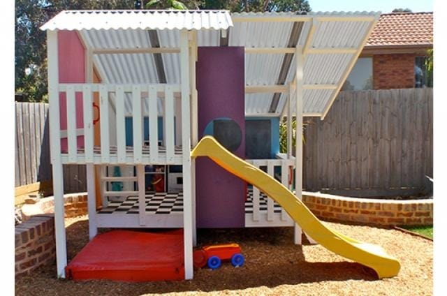 Mega Triplex Cubby House different view of a fully painted and furnished house with yellow slide and sandpit