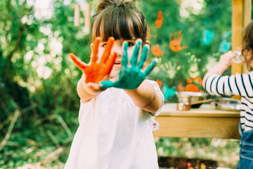 Child playing outdoors at the Plum Discovery Mud Pie kitchen