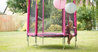 Half image of4.5ft Junior Kids Trampoline Pink toddler trampoline on outdoor background with little girl sitting at the trampoline entrance