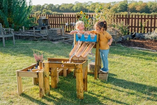 two kids playing with the forest water run on grass