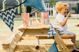 Close up image of a little boy sitting at the Image of a little boy arranging a snack in the Picnic Table With Umbrella and 2 little kids sitting on the mat outdoor while waving and smiling