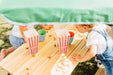 Close up image of the wooden table of Picnic Table With Umbrella with 2 children enjoying the snack